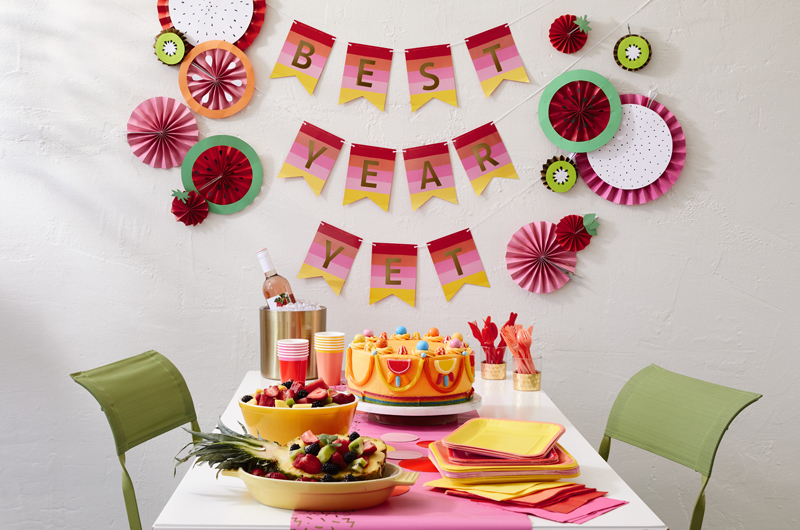 Uma mesa de férias de verão cheia de frutas e bolos. Um banner de cores pop em segundo plano.