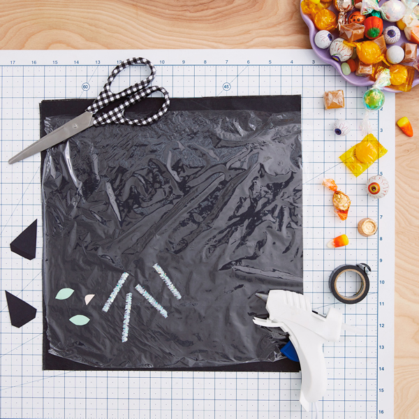 Para fazer o papel do gato preto, você vai precisar de lenço de papel, papel de embrulho, tesoura, cartolina, cola quente, fita adesiva, limpador de cachimbo e, claro, salgadinhos!
