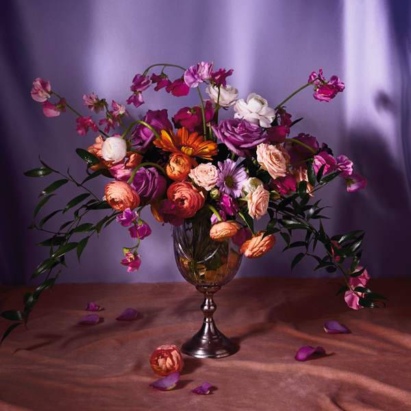 Um buquê de flores em um vaso de metal com iluminação suave.