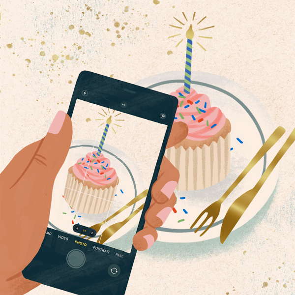 Uma representação manual de um iPhone que atira em um cupcake com uma vela e polvilha em um prato com garfo e faca de ouro.