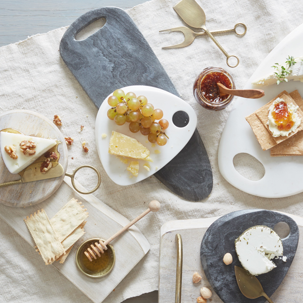 Uma foto de uma mesa de aperitivos exibindo uma variedade de queijos, frutas e pratos simples & amp; lt; panela& gt; lembranças de artistas decorativos