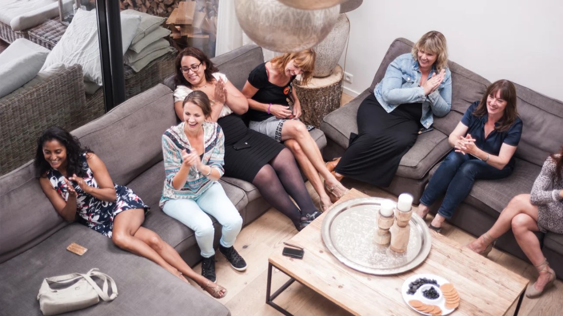 Vista aérea de um grupo de mulheres sentadas em um sofá em uma festa em casa.
