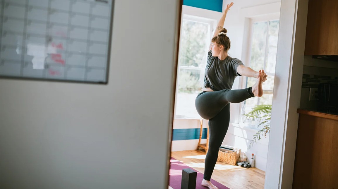 Uma mulher faz alongamentos de ioga nos dias de descanso. Nos outros dias, ela treina músculos diferentes. Tente treinar músculos opostos para manter o corpo equilibrado.